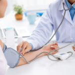 Doctor checking blood pressure of the patient, selective focus